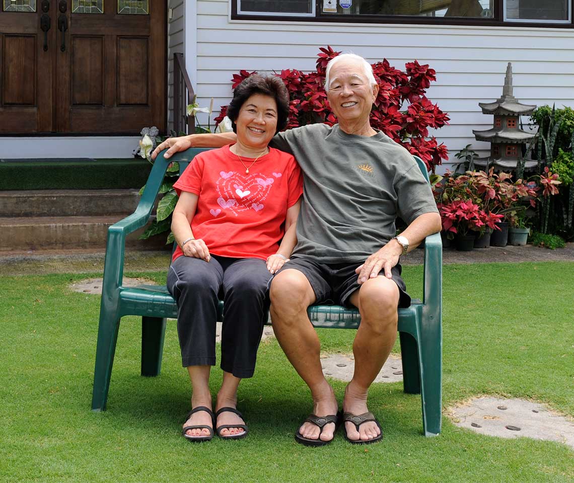 An-older-couple-sitting-in-front-of-a-house-in-Hawaii