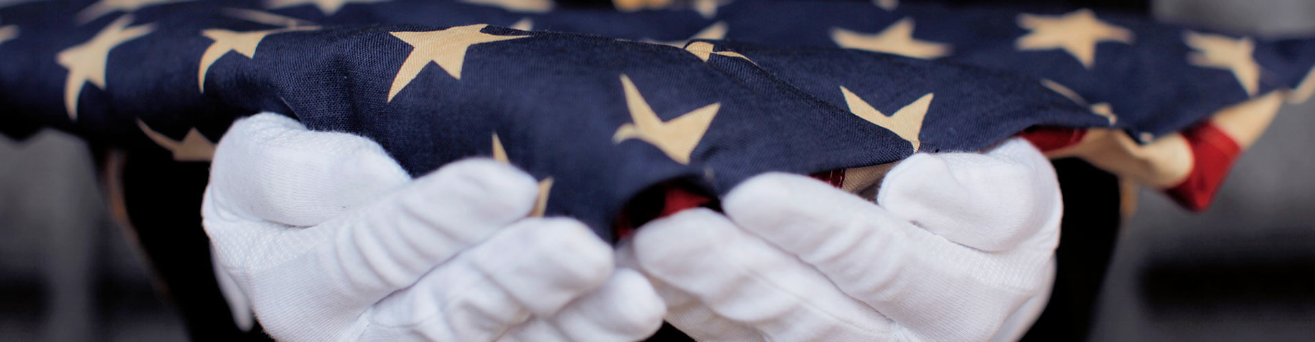 A-military-personnel-wearing-white-gloves-and-holding-a-folded-American-Flag